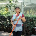 Woman cleaning outdoors with a broom in a city street during summer.